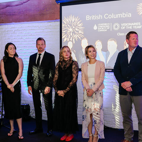 Participants stand together on stage as speakers recognize the Visionaries class during the evening celebration.