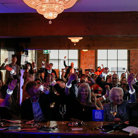 Guests raise glowing bracelets together during an interactive moment at the Visionaries gala celebration.