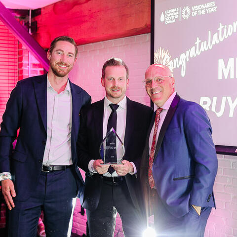 Three participants stand together proudly with the top fundraising award during the Visionaries gala celebration.