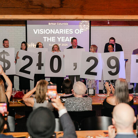 Participants on stage hold fundraising numbers high as guests applaud the $240,297 campaign achievement.