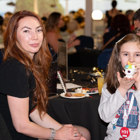 An adult guest and a child sit together at a reception table, sharing a quiet moment during the event.
