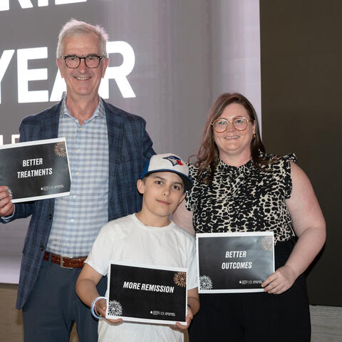 Special  guests on stage hold signs for better treatments, more remission and better outcomes for blood cancer patients.