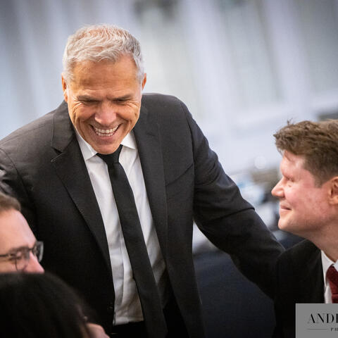 Participants connect and share a light moment at their table, leaning in as conversation flows during an elegant evening fundraising event.